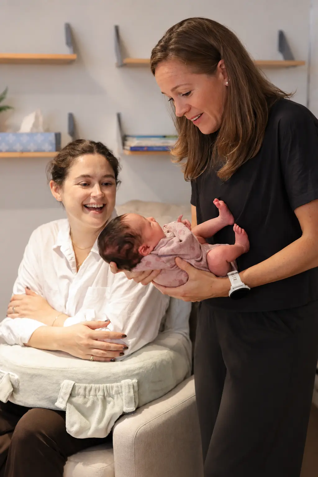 Groove practitioner holding a newborn alongside a new mother